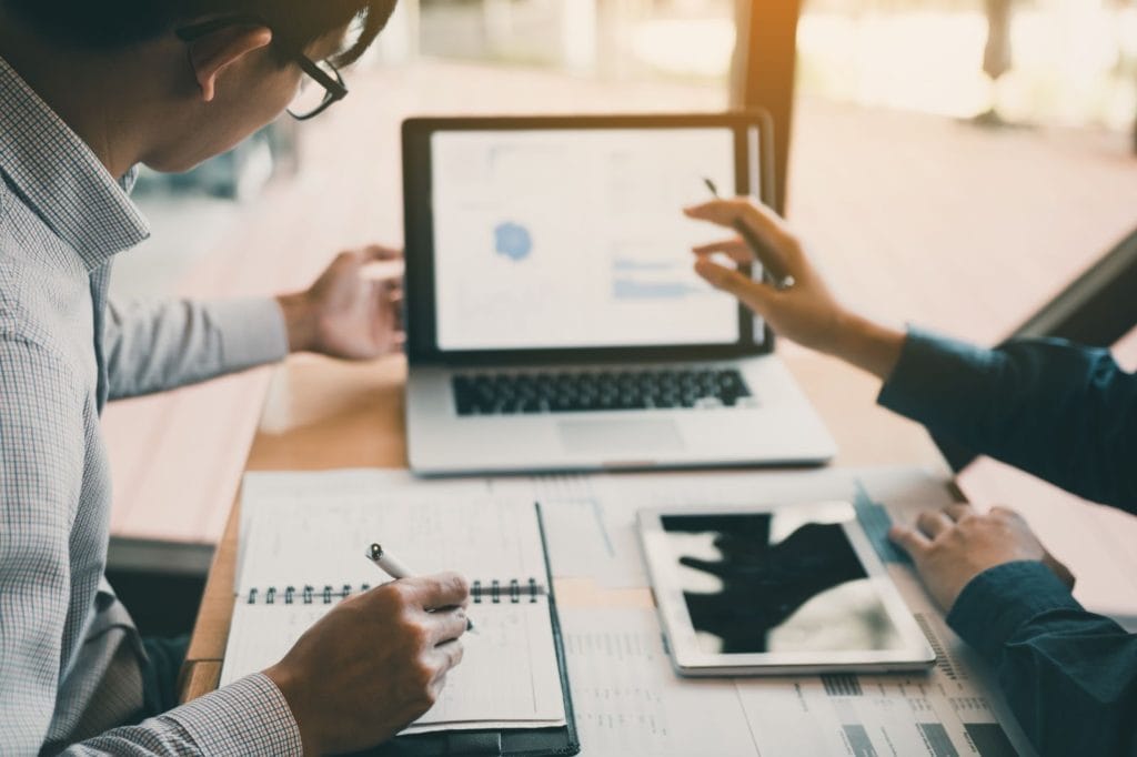 Two people working on financial reports explaining service to client