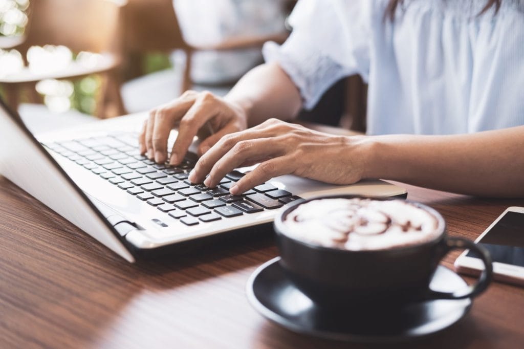 Person Working at Coffee Shop using software on laptop