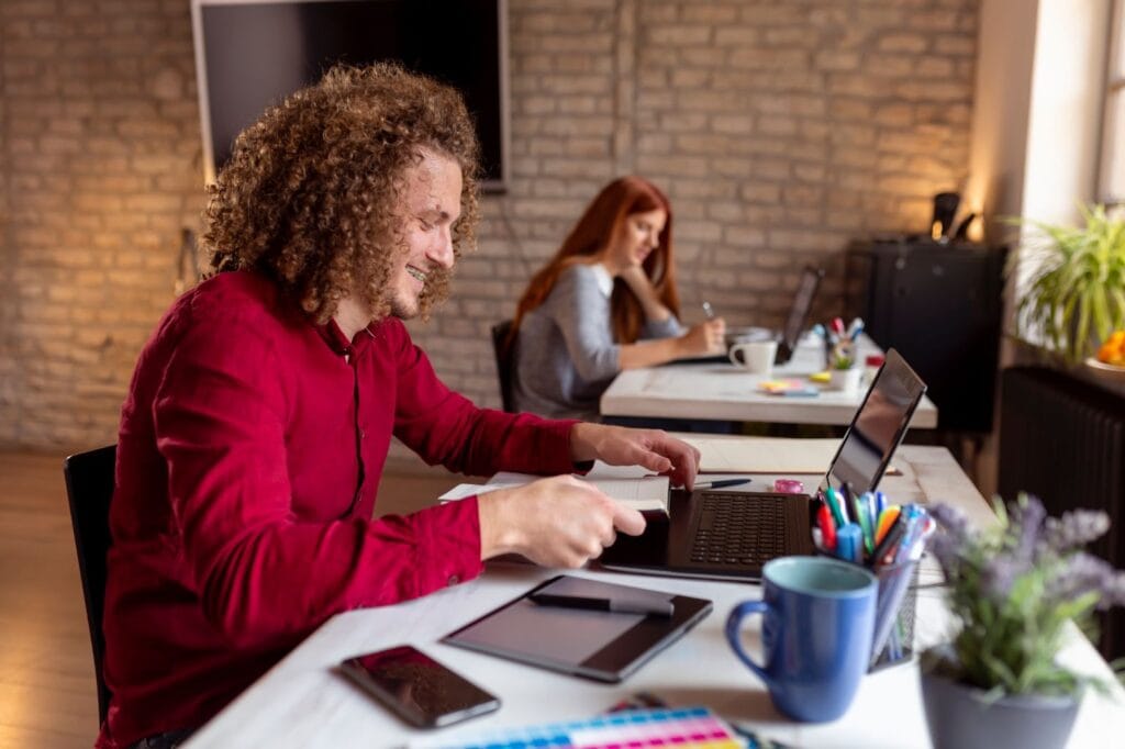 Two people working at separate desks with laptops