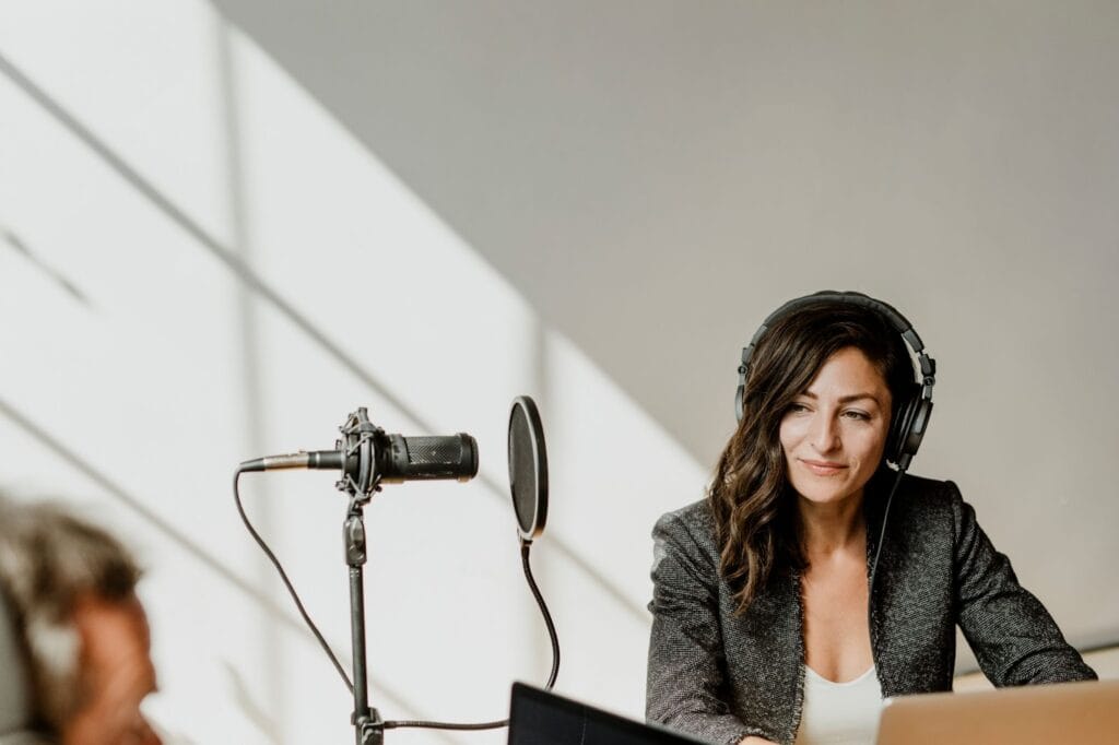 Woman with headphones, laptop and speaker recording audio