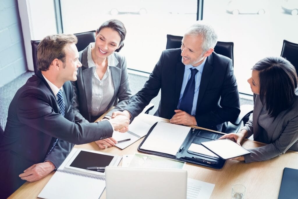 Group of professional meeting at table, two shaking hands
